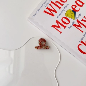 Close-up of a mini marble-patterned hair claw on a decorative wave acrylic plate