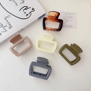Flat lay of five Morandi colored square hair claws with aesthetic book and card backdrop
