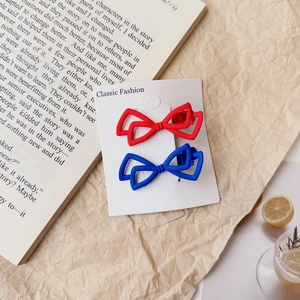 Détail de barrettes à cheveux nœud mat rouge et bleu avec motif géométrique ajouré