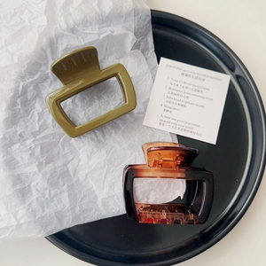 High-angle shot of retro hair claw clips in olive green and tortoiseshell patterns on a tray