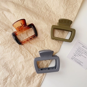 Three rectangular resin hair claws in amber, olive green and grey on paper background