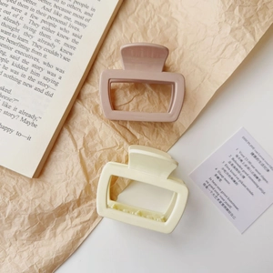 Detail of square cutout hair claws in dusty pink and beige colors on vintage book