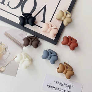 Pinces à cheveux papillon mates aux couleurs Morandi sur un fond minimaliste épuré