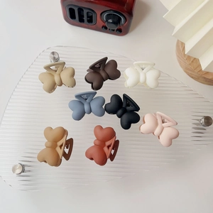 Gros plan détaillé de 8 barrettes papillon mates aux couleurs Morandi variées sur support