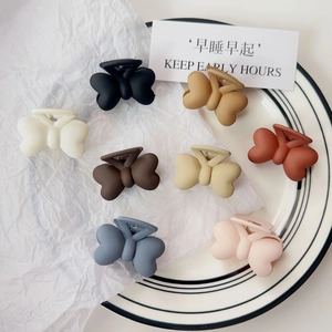 Lot de huit pinces à cheveux papillon mates aux couleurs Morandi sur une assiette