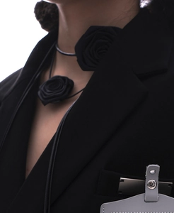 Détail d'un ras de cou fleur de camélia 3D noir associé à un blazer noir chic