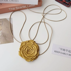 Détail d'un collier ras de cou rose en tissu jaune fait main avec une longue corde marron