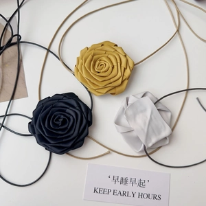 Détail de colliers roses en tissu faits main en noir, jaune et gris avec texture satinée