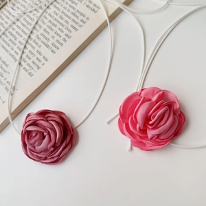 Détail macro de colliers ras du cou en rose satinée faits main en rose et mauve sur blanc