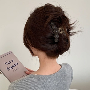 Detailed view of dark grey bead shark clip hair accessory on a person's hairstyle