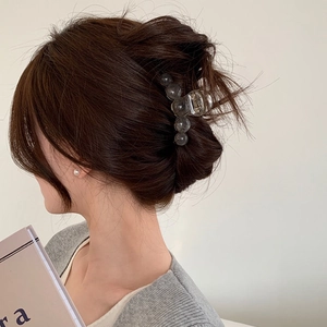 Detail of amber texture hair claw clip holding hair in a stylish half-up bun hairstyle
