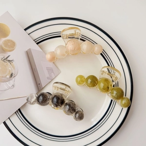 Detailed view of amber-textured acrylic hair claws in peach, olive, and marbled grey finishes