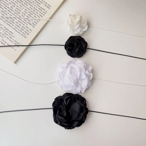 Détail de quatre accessoires de roses faits main en noir et blanc avec rubans
