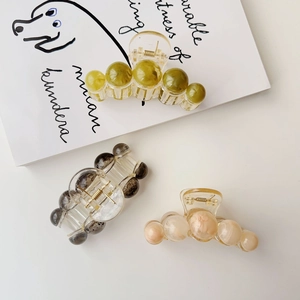 Detail view of marble textured amber-like resin hair claws in three elegant colors