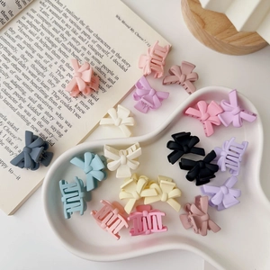 Detail view of colorful matte bow hair claws in pink, blue, and cream on a decorative tray