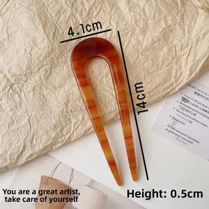 Macro shot of U-shaped acetate hair pin with amber tortoise shell pattern and glossy finish