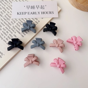 Close-up of matte butterfly bow hair claws in various pastel colors on a vintage book