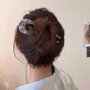 U-shaped acetate hair pin with marble texture shown on elegant bun hairstyle