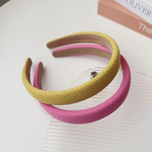 Detail view of woven fabric texture on padded yellow and pink headband set on desk