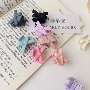 Detail of matte mini bow hair claws in various pastel colors on an aesthetic background