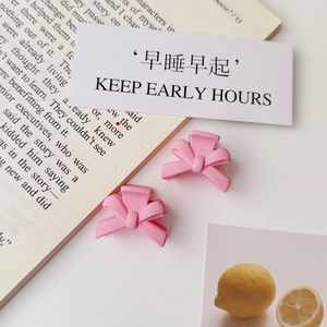 Detailed close-up of matte pink bow hair clips on a clean decorative background