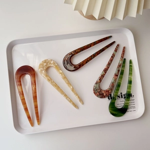 Detailed view of U-shaped acetate hair pins in various marble and tortoiseshell patterns