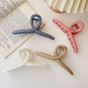 Extra large 15cm matte claw clips in four colors on a minimalist desk setting