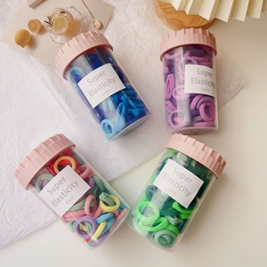 Close-up of four jars containing colorful high-elastic hair ties for kids