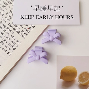 Close-up of two matte lavender bow hair clips on a creative stationery background