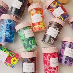 Close-up of candy-colored elastic hair ties in transparent jars with pink lids