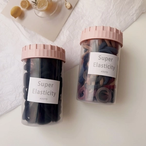 Close-up of high elasticity hair ties in transparent jars with pink screw caps