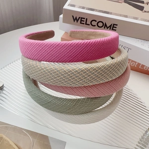 Close-up of four thick padded headbands in pink, plaid, green and beige woven fabric