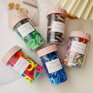 High elasticity kids hair ties set in five colorful jars on a bright white background