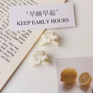 Close-up of cream white matte bow hair clips on a decorative lifestyle background