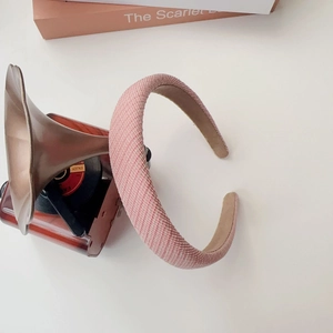 Pink woven padded headband with anti-slip lining shown next to retro props on white background