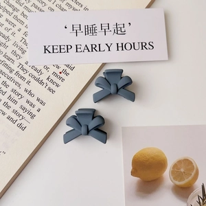 Detailed view of matte blue and dark grey mini bow claw clips for side hair styling