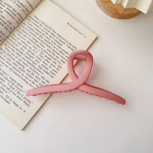 Close-up of a 15cm oversized matte pink hair claw clip resting on an open book