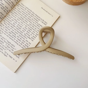 Matte beige oversized hair claw clip resting on a book for casual styling