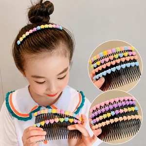 Détail de breloques étoiles et cœurs macaron sur un long peigne à cheveux noir pour enfants