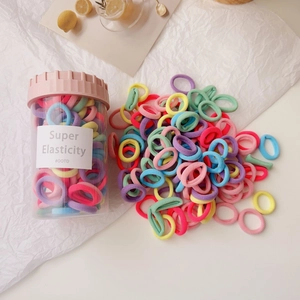 Detailed macro view of colorful high-elastic hair ties stored in a clear cylinder jar