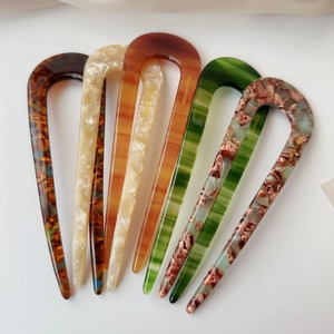 Macro view of five assorted acetate U-shaped hair forks with marble and tortoise textures