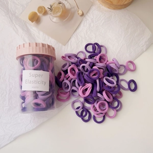 Close-up of colorful high-elastic hair ties in a transparent jar with towel texture