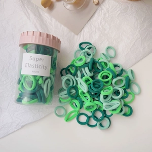 Macro detail of green hair elastics set with a transparent storage jar and elastic bands