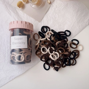 Close-up of high elasticity hair ties in earth tones stored in a clear jar with a pink lid