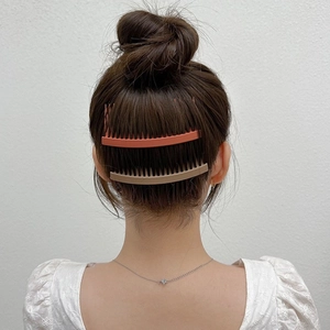 Detail of multi-tooth hair finishing combs in orange and khaki for securing loose hair strands