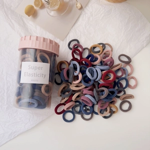 Close-up of candy colored hair ties in a transparent storage jar with pink lid