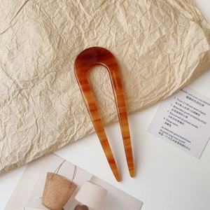 Close-up of amber patterned acetate U-shaped hair fork with elegant French engraving