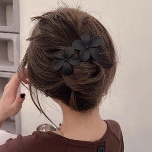 Vue détaillée de deux pinces à cheveux fleurs noires mates sur un chignon de modèle