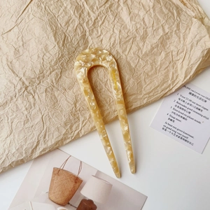 Close-up of modern U-shaped acetate hair pin with elegant beige marble pattern texture