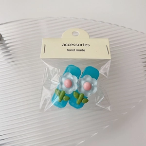 Dettaglio di due fermagli per capelli con fiori blu fatti a mano su cartoncino retail
